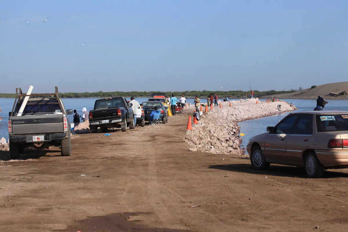 Pescadores y vehículos sobre el espigón de Las Glorias, en la barra de Navachiste, Guasave.